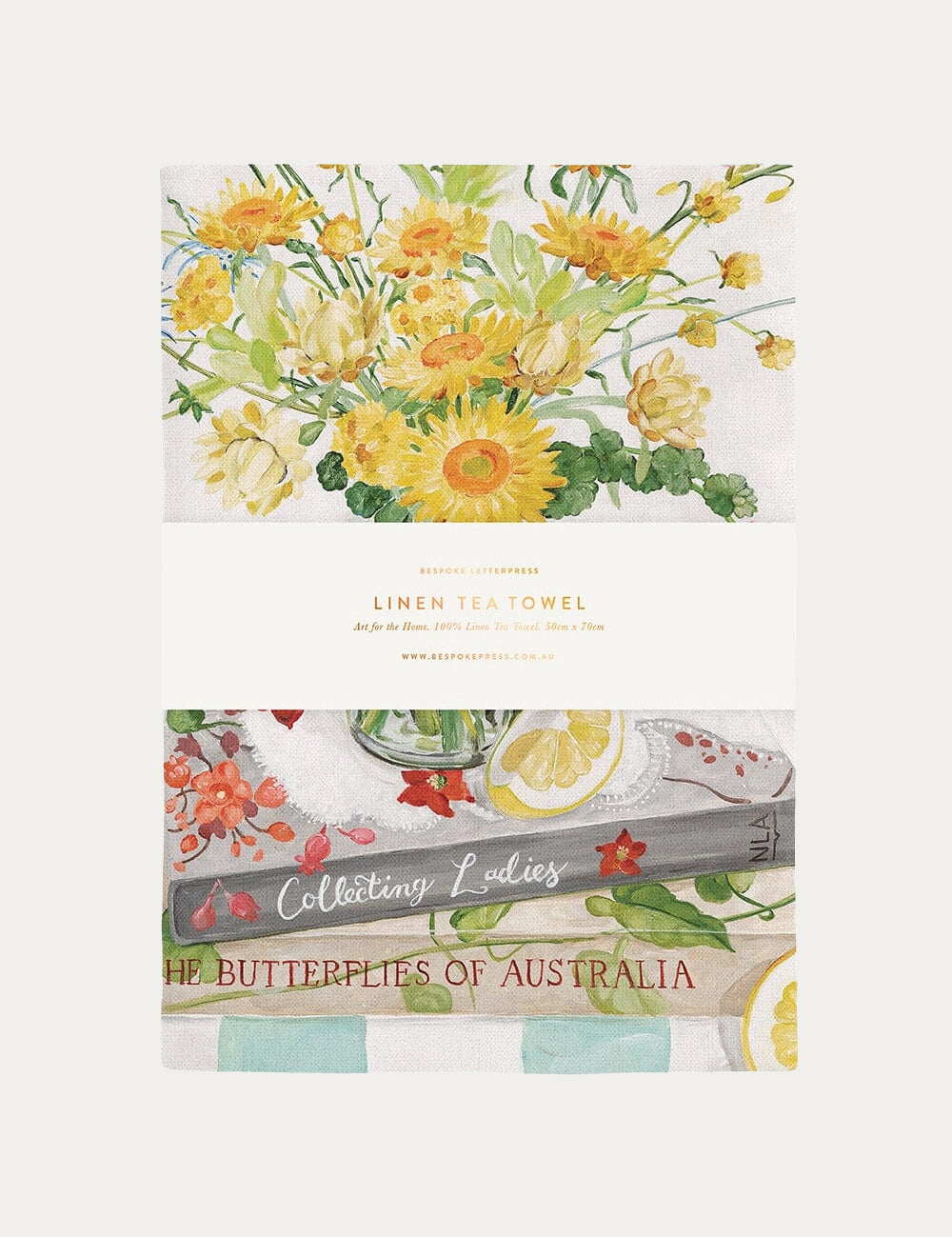 A square linen tea towel featuring a watercolor floral design with yellow flowers, green leaves, and tea-themed illustrations including lemons, a teapot, and the text 'The Butterflies of Australia' and 'Celebrity Values'. A white paper band wraps around the center with the brand name 'The Butterfly of Australia' and product details.