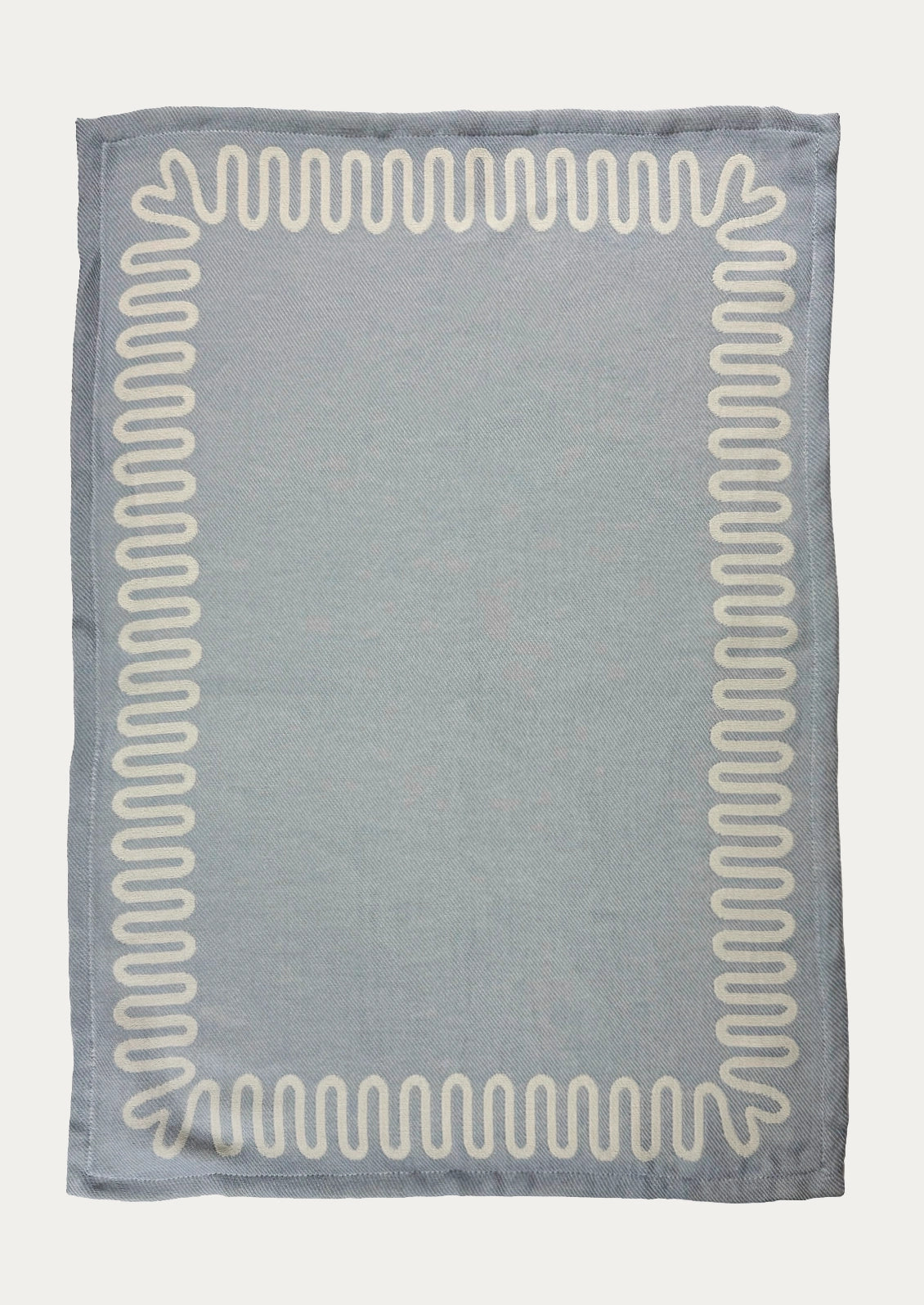 A blue dish towel with white squiggle border.