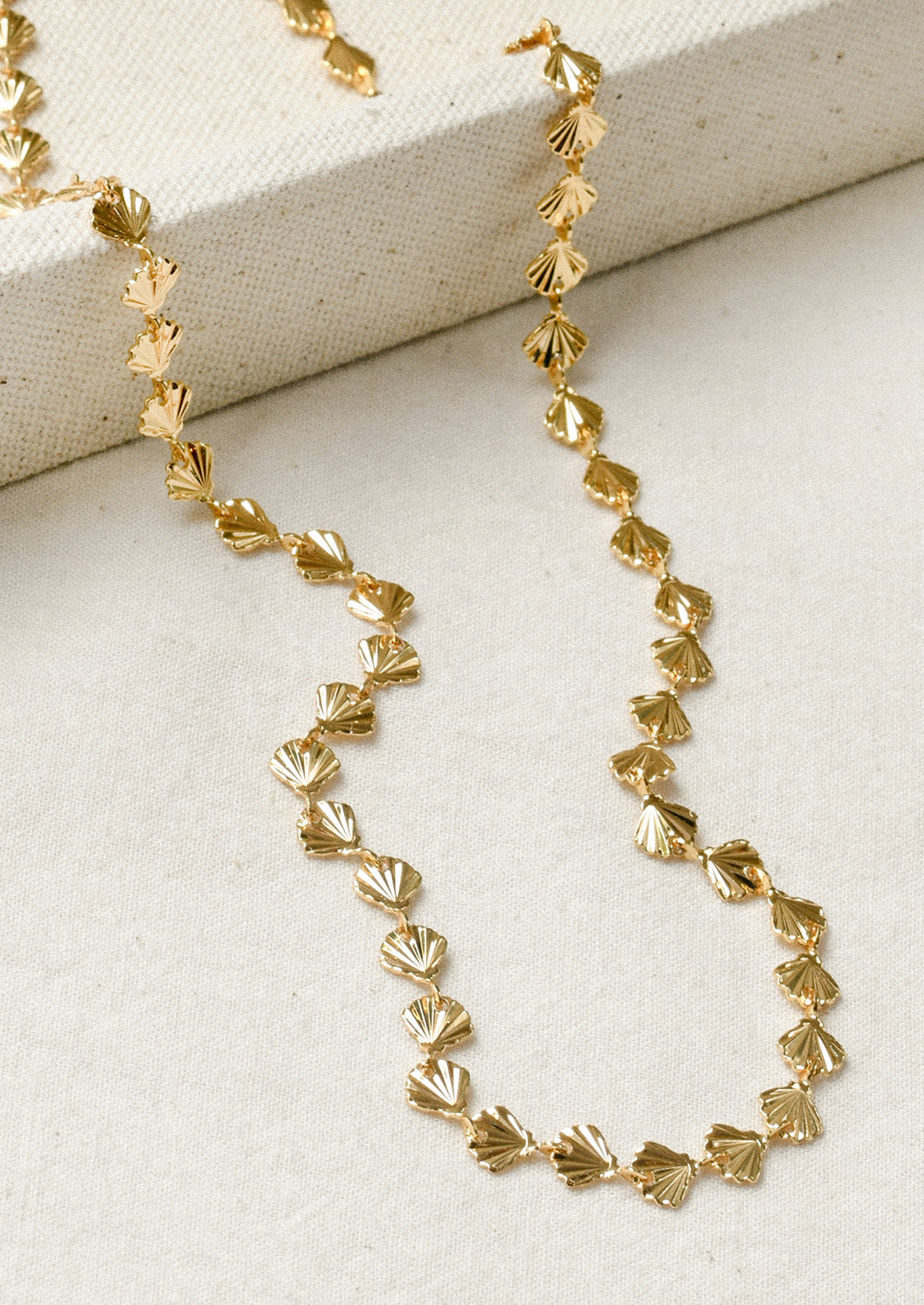A gold necklace composed of tiny gold seashells.