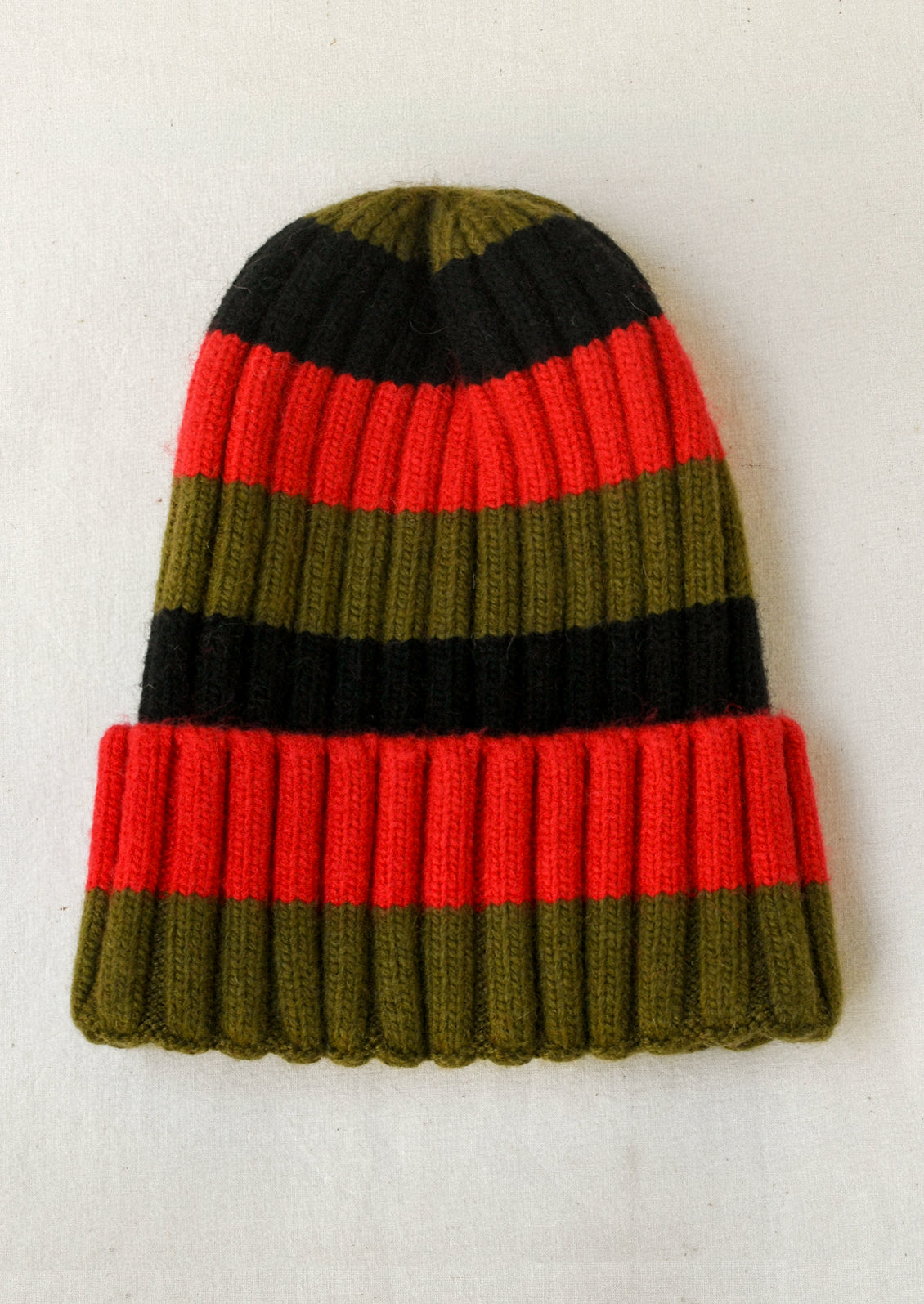 A cashmere-blend ribbed beanie with red, black, and olive stripes.