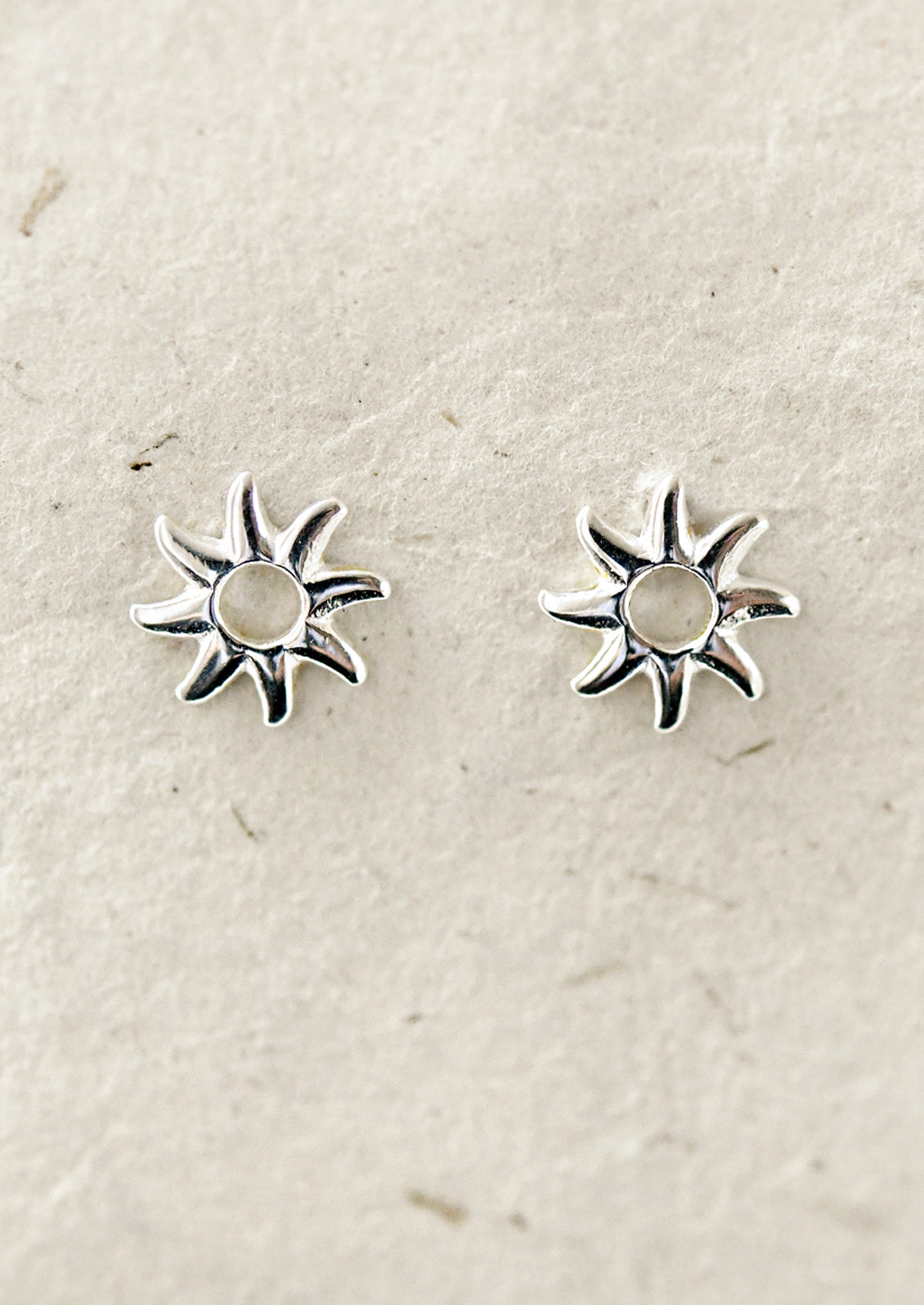 A pair of silver sun shaped stud earrings.