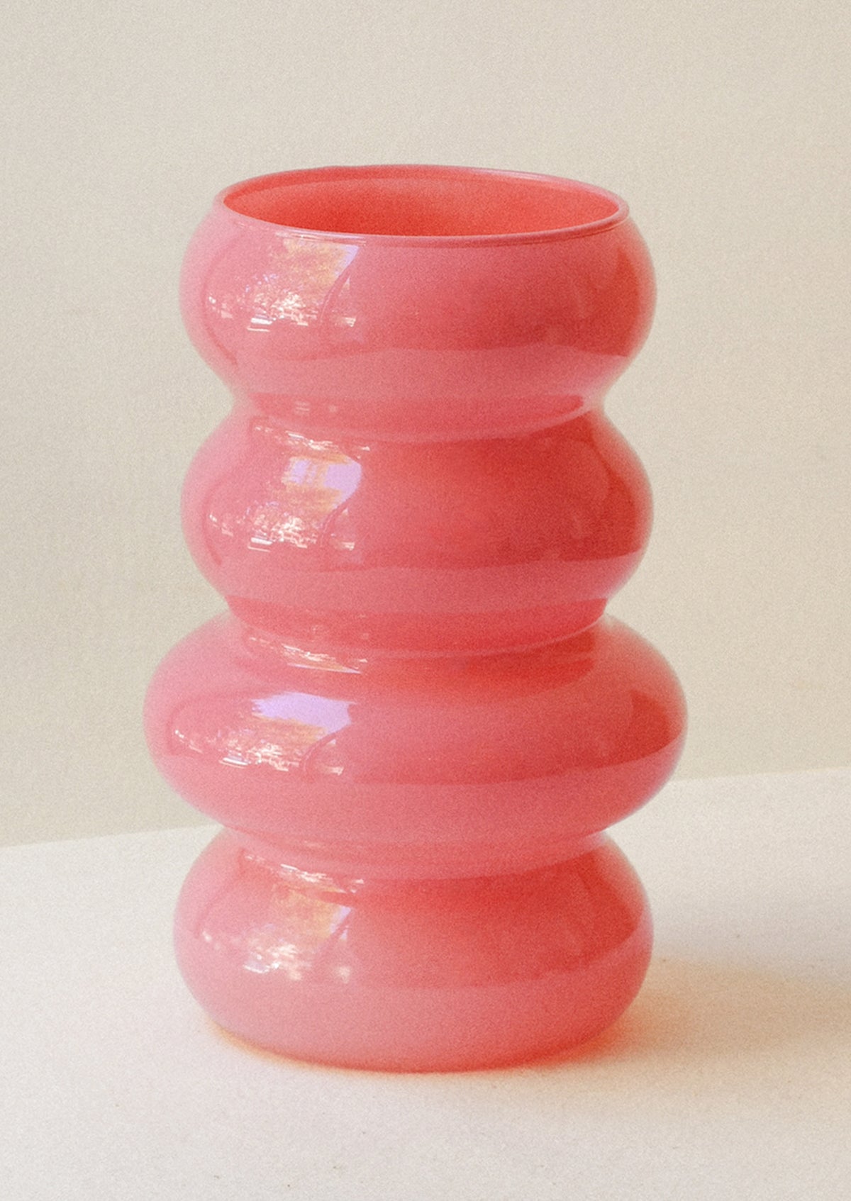 A wavy glass vase in a tulip pink color.