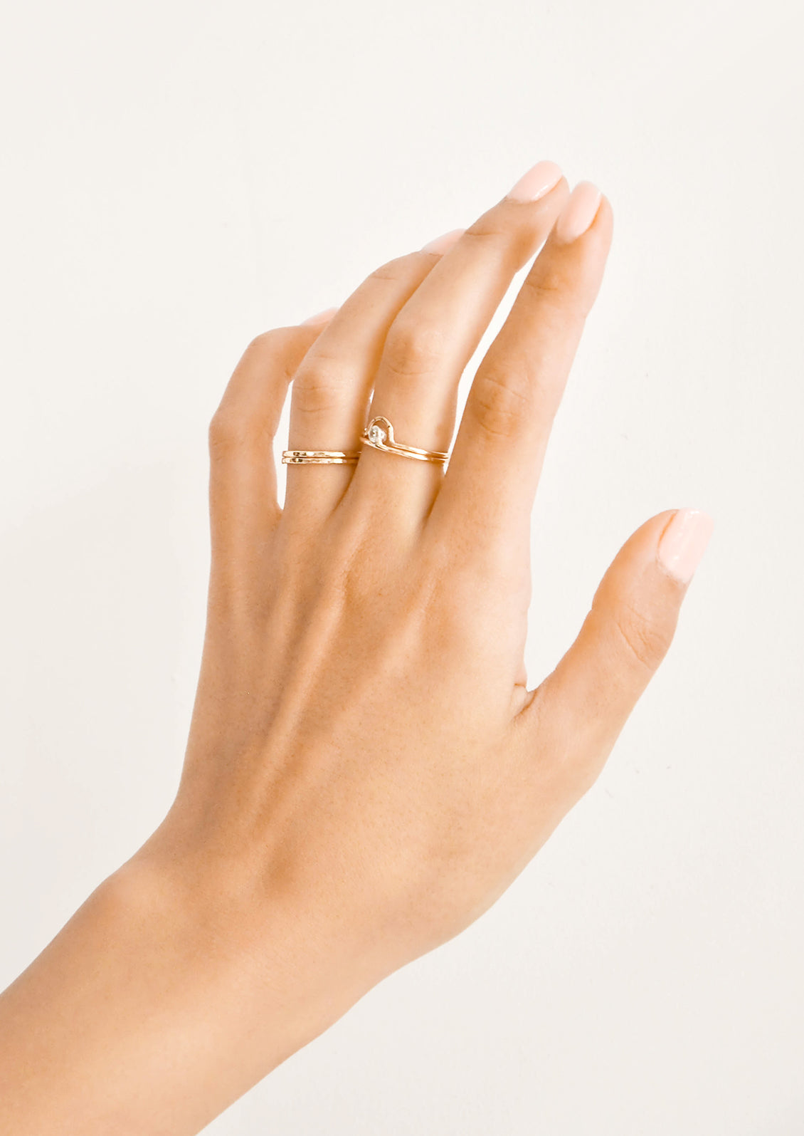Woman's hand with gold rings on her ring and middle fingers.