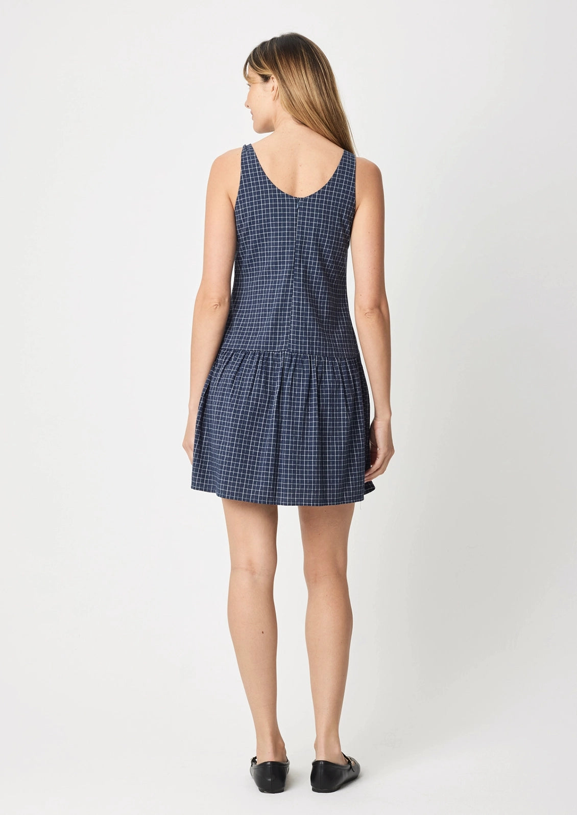 A person wearing a navy mini dress with white check pattern.
