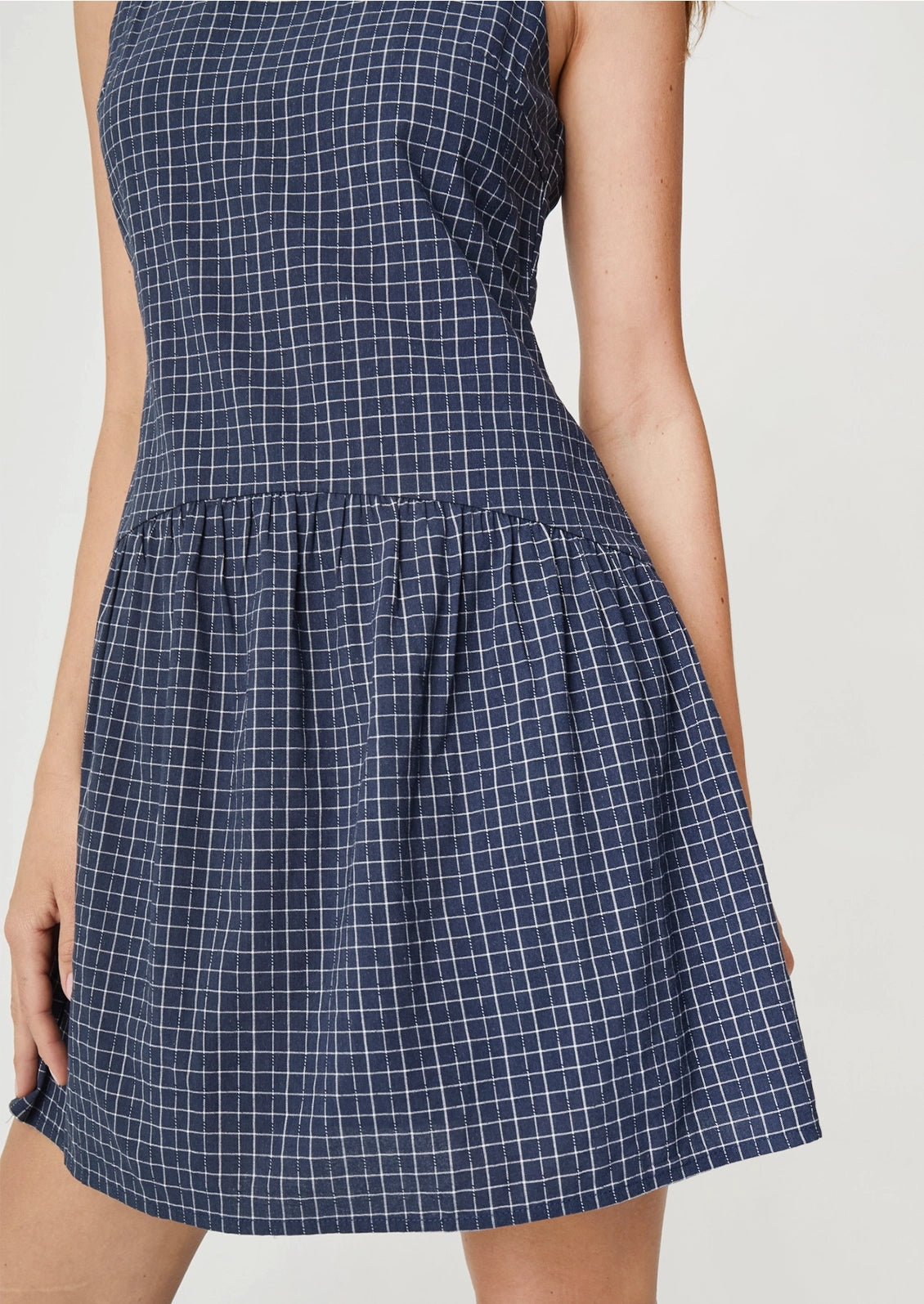 A person wearing a navy mini dress with white check pattern.