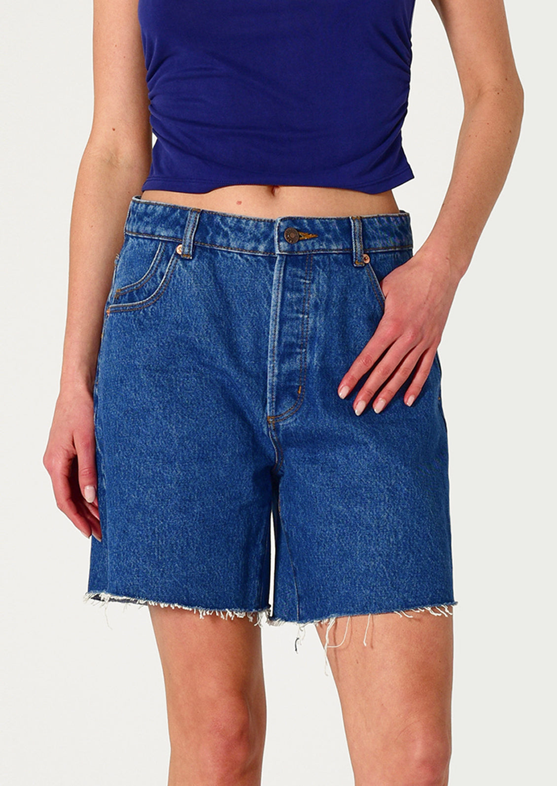 Person wearing blue denim shorts and a purple top on a white background