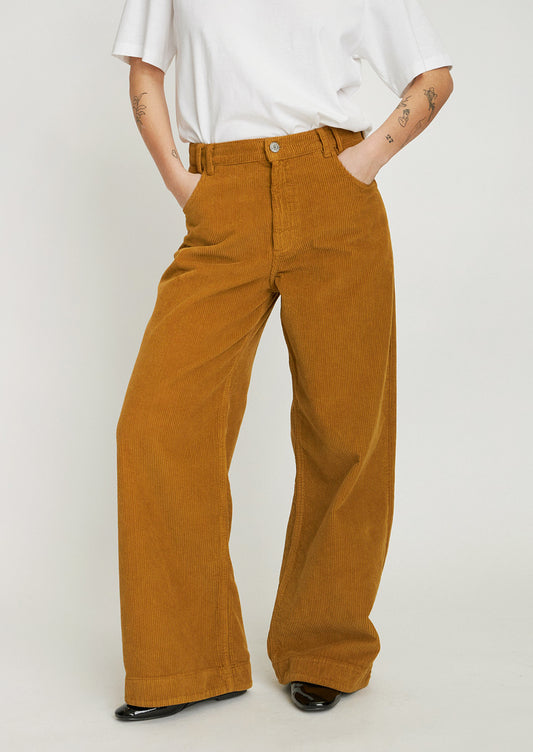 A woman wearing a pair of ochre colored wide leg corduroy pants.
