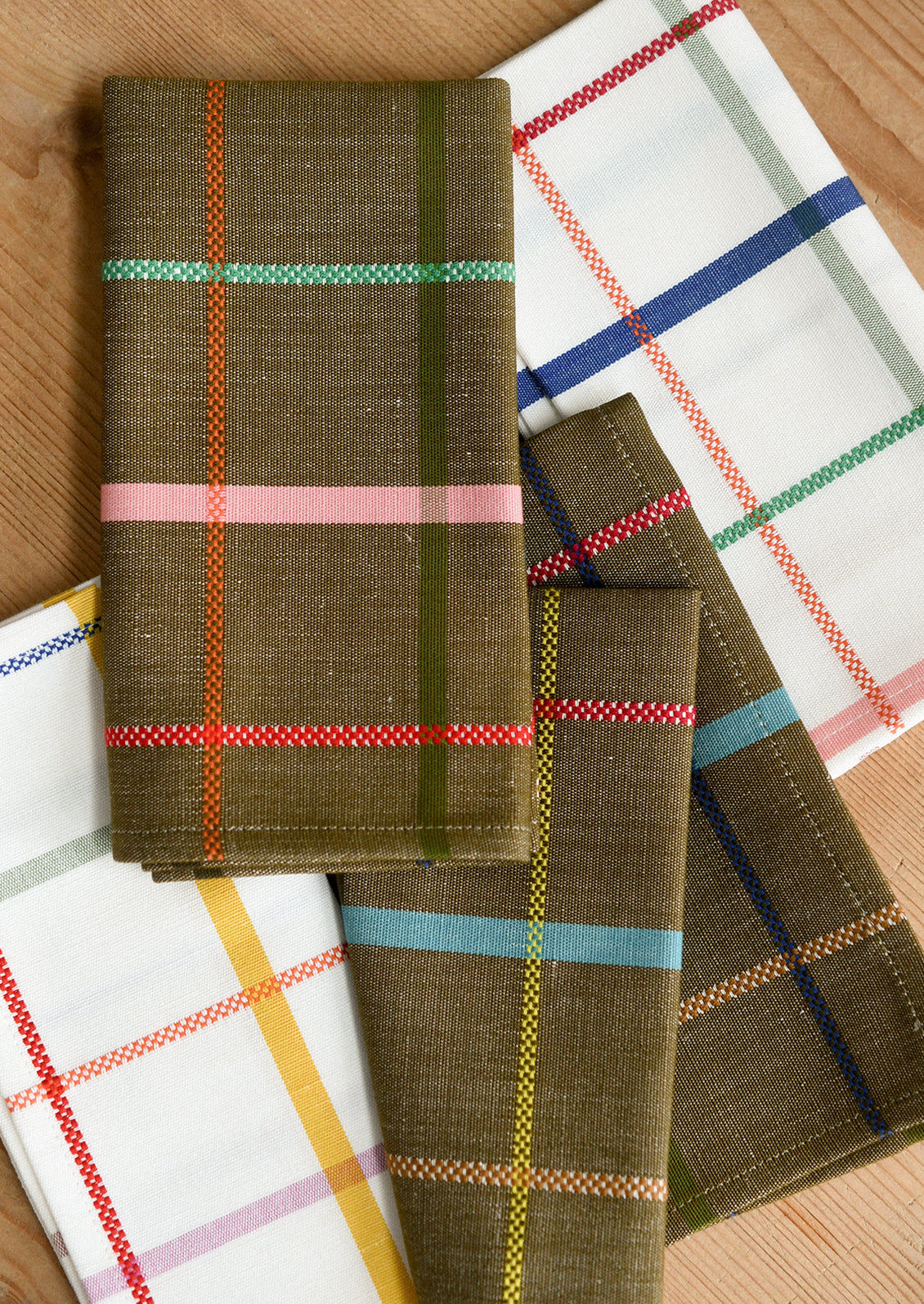 Folded plaid napkins arranged on a wooden surface. 
