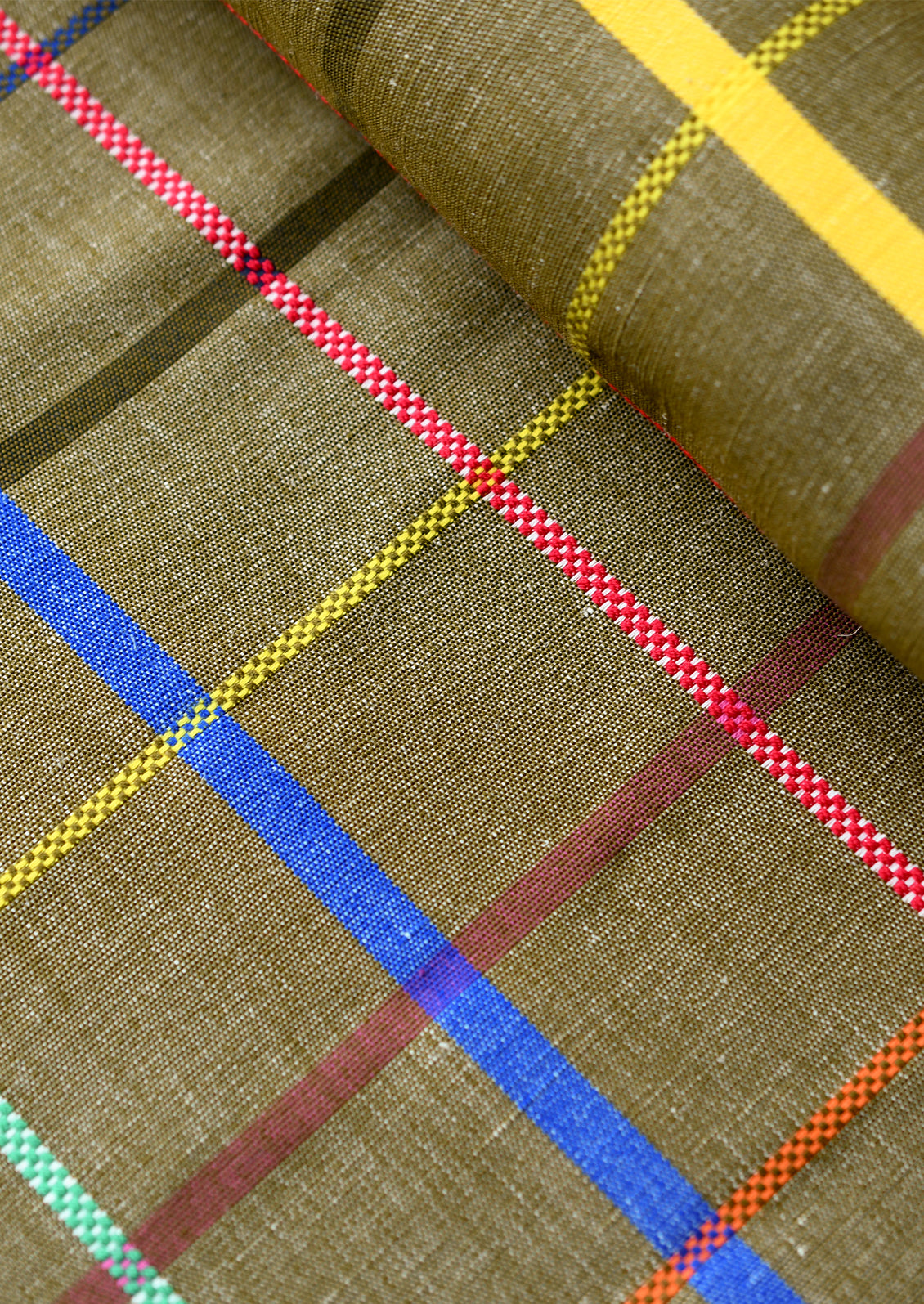 Close-up of a woven fabric with an olive brown base and a multicolor plaid pattern featuring red, yellow, blue, and green stripes.