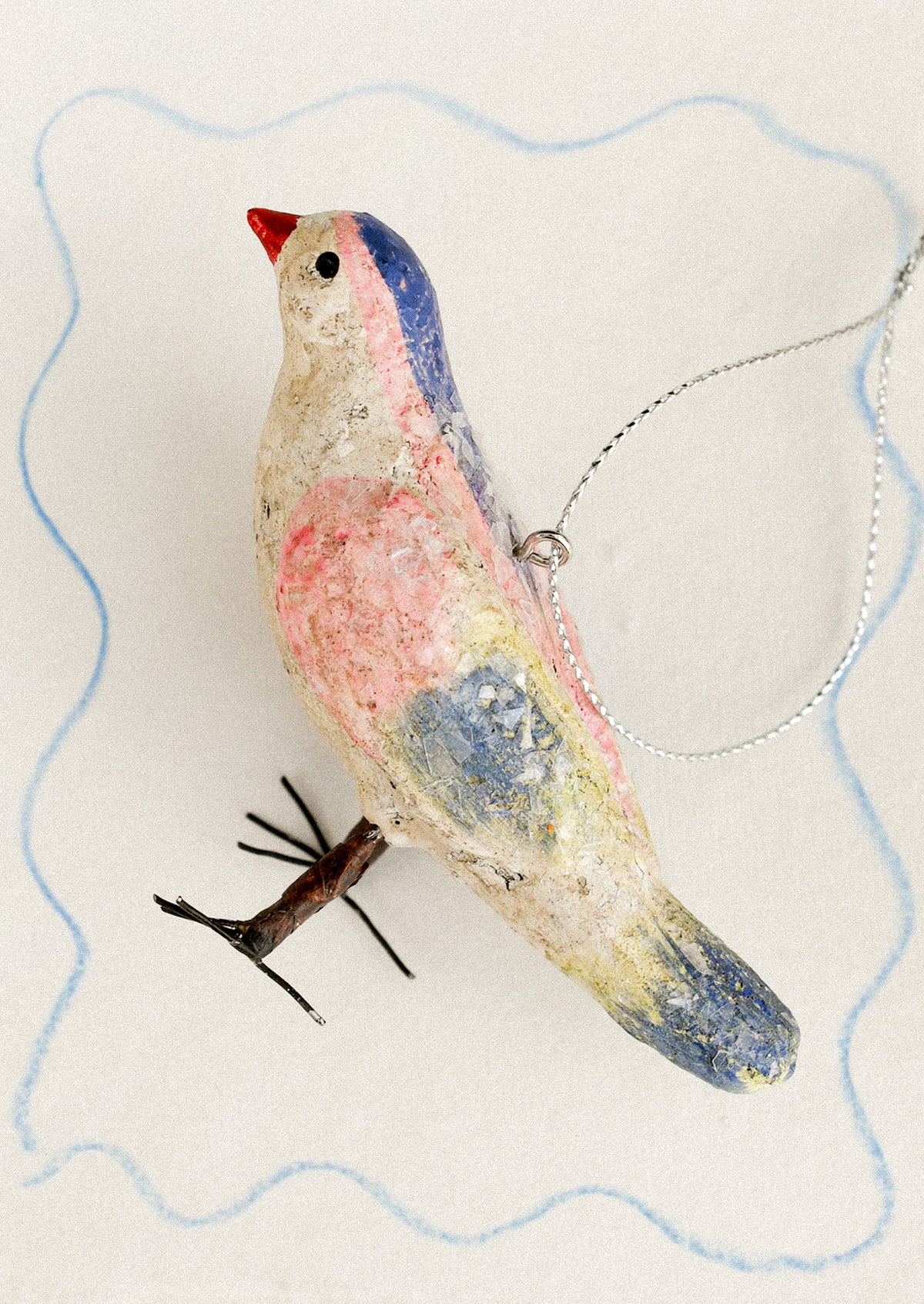 A holiday ornament made from paper mache, depicting a small bird with colorful feathers.