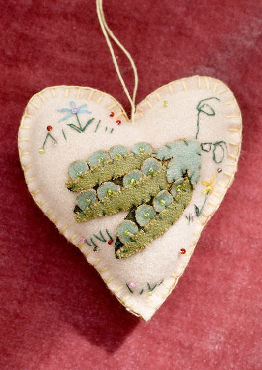 A felt heart shaped ornament with vegetable pea pod motif.