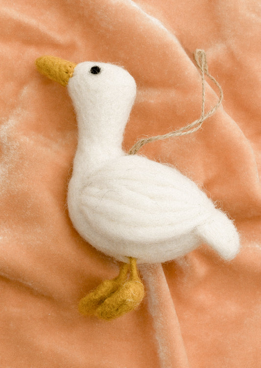 A white felt bird ornament with yellow feet and beak.