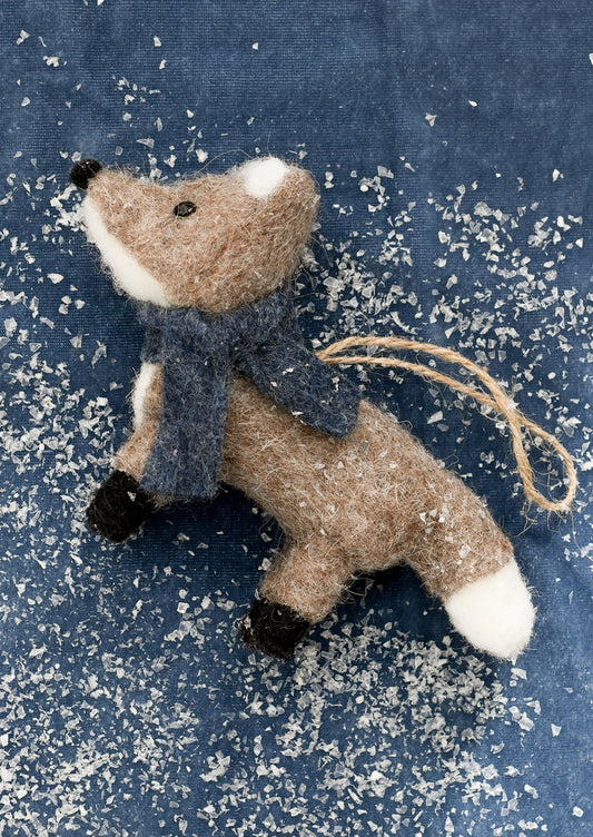 Felted fox ornament with a scarf on a textured blue background