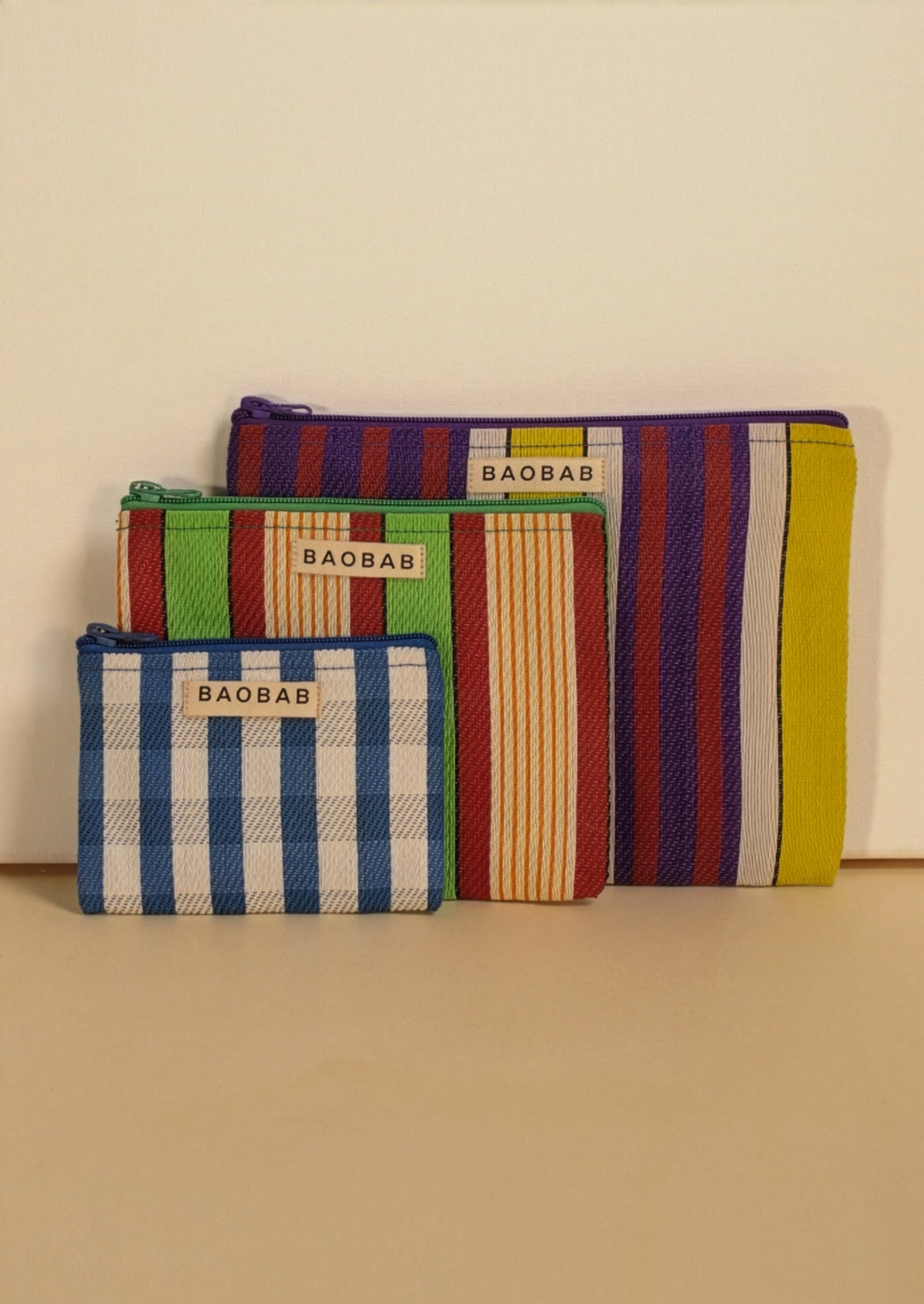 A set of three striped flat pouches in assorted tones of blue, green, red and yellow.
