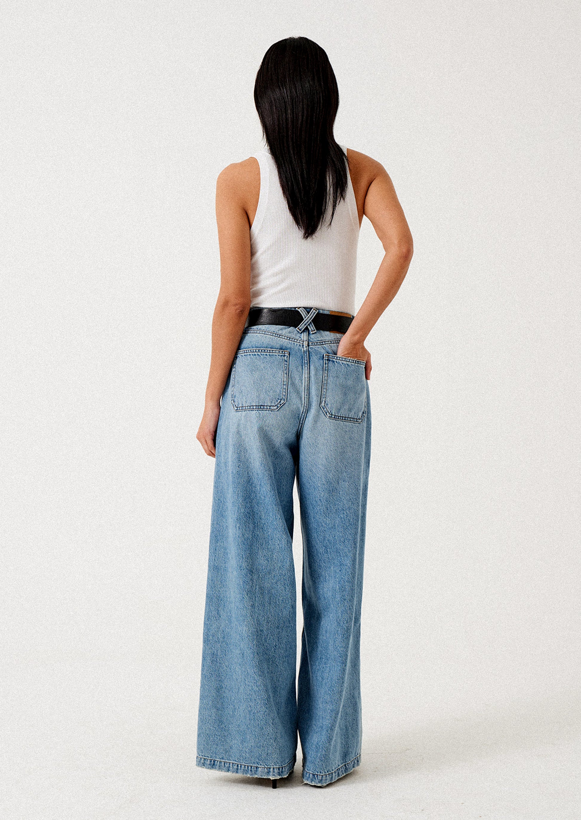 A person wearing a pair of medium wash wide leg jeans.