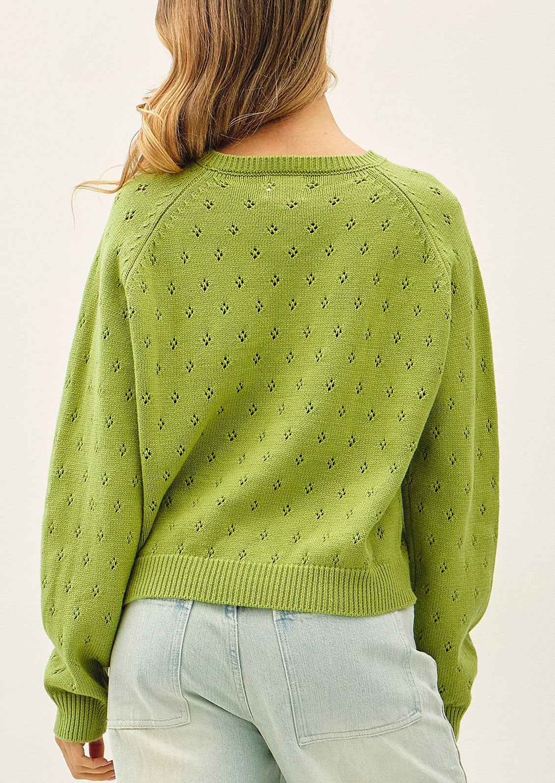 A woman wearing a light green knit cardigan sweater.