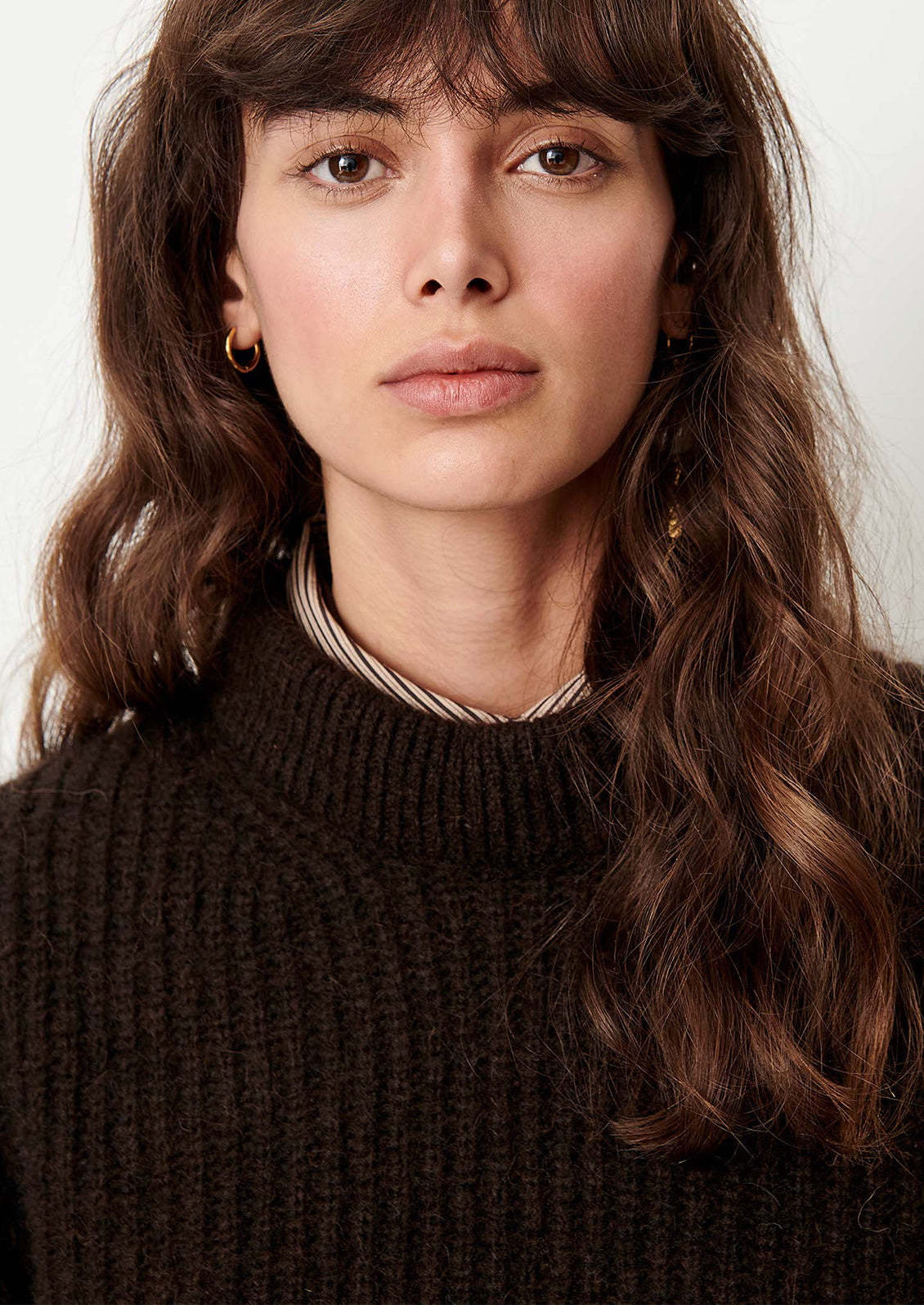 A person wearing a knit sweater in brown with padded crewneck.