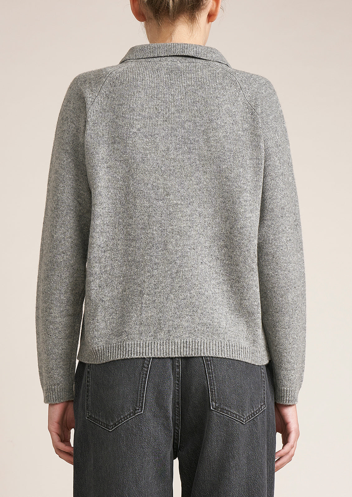 A woman wearing a heather grey long sleeve sweater.