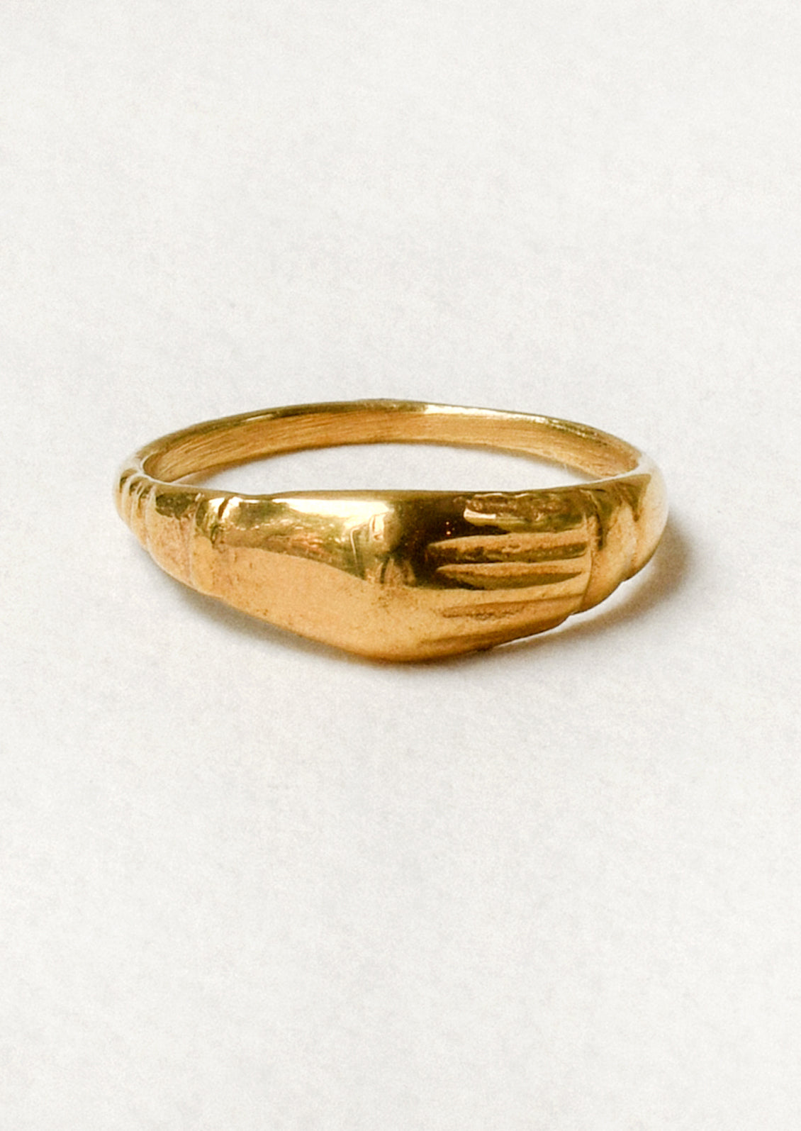 A gold ring with a unique engraved design on the front.