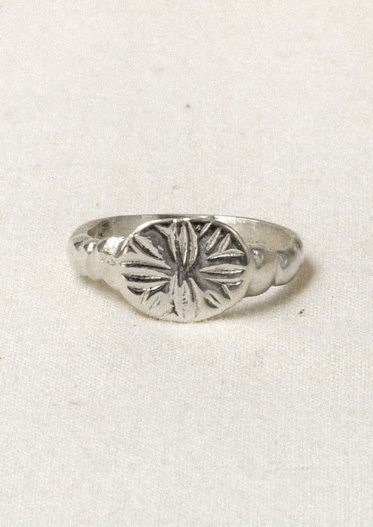 A sterling silver ring with a star-like design engraved on the front.