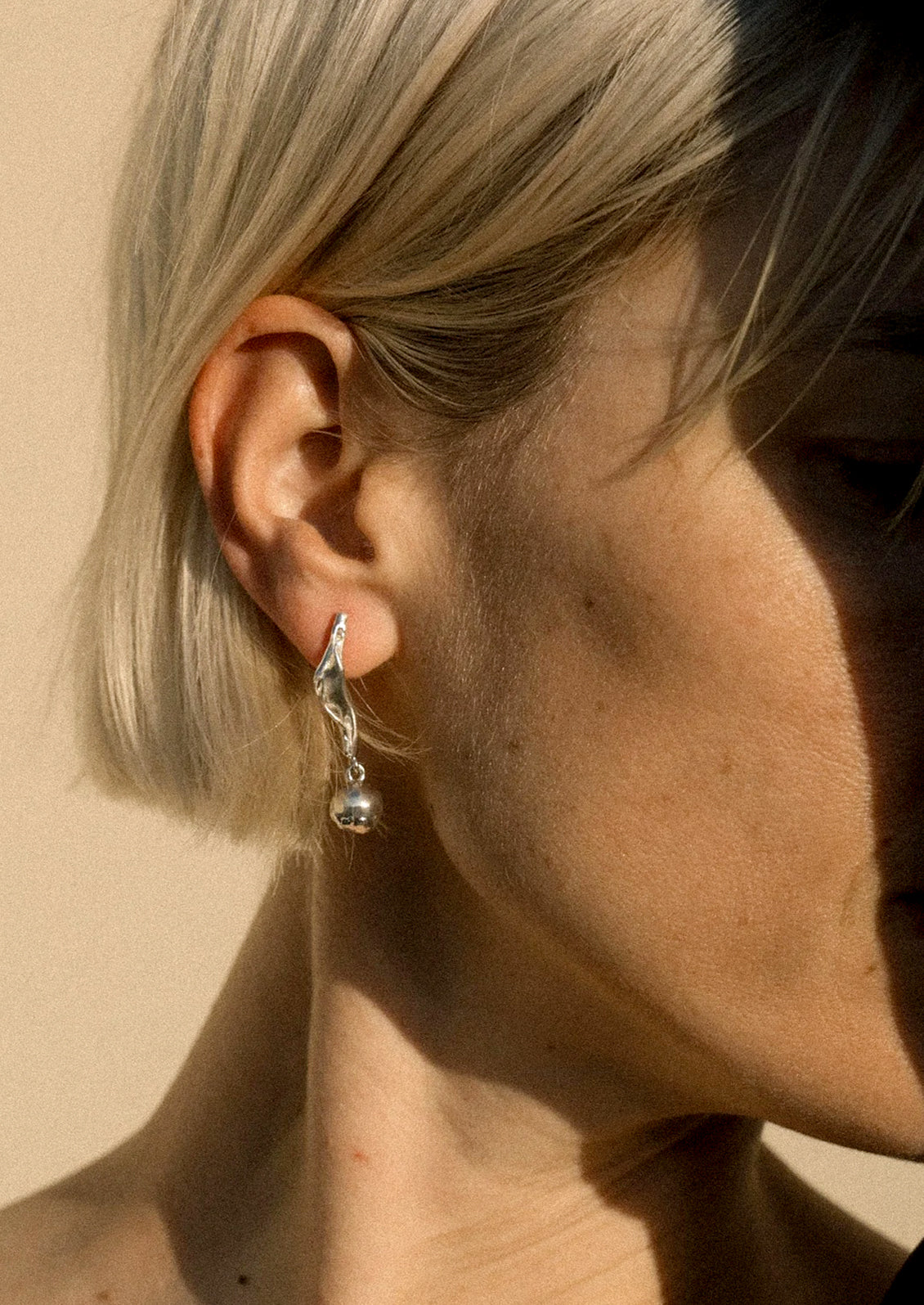 A woman wearing a sterling silver drop earring.