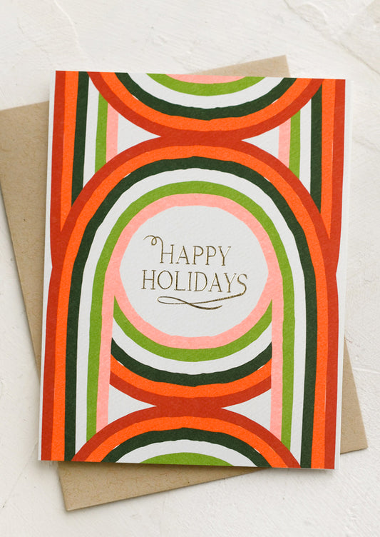 A holiday card with geometric arch print in red and green, text reads "happy holidays".