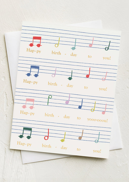 A card with rainbow colored sheet music to the tune of Happy Birthday song.