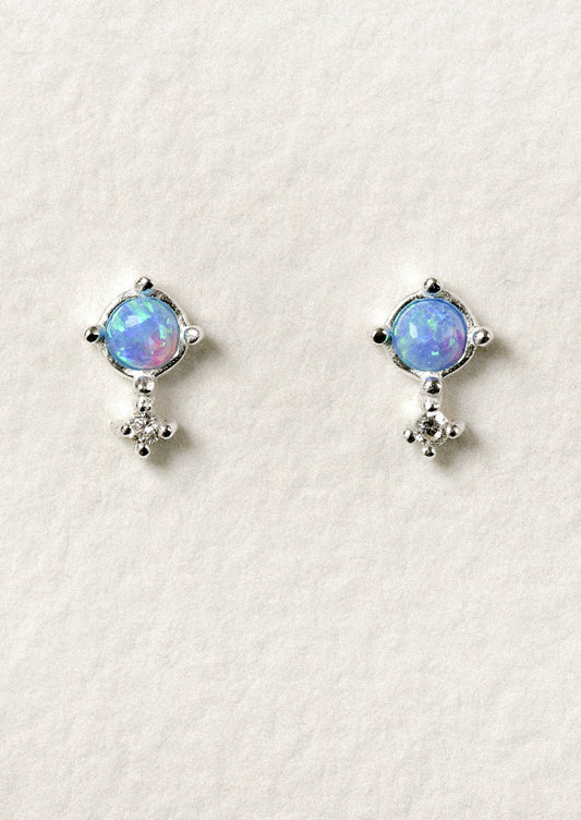 A pair of sterling silver stud earrings with a vibrant blue opal set in the center.