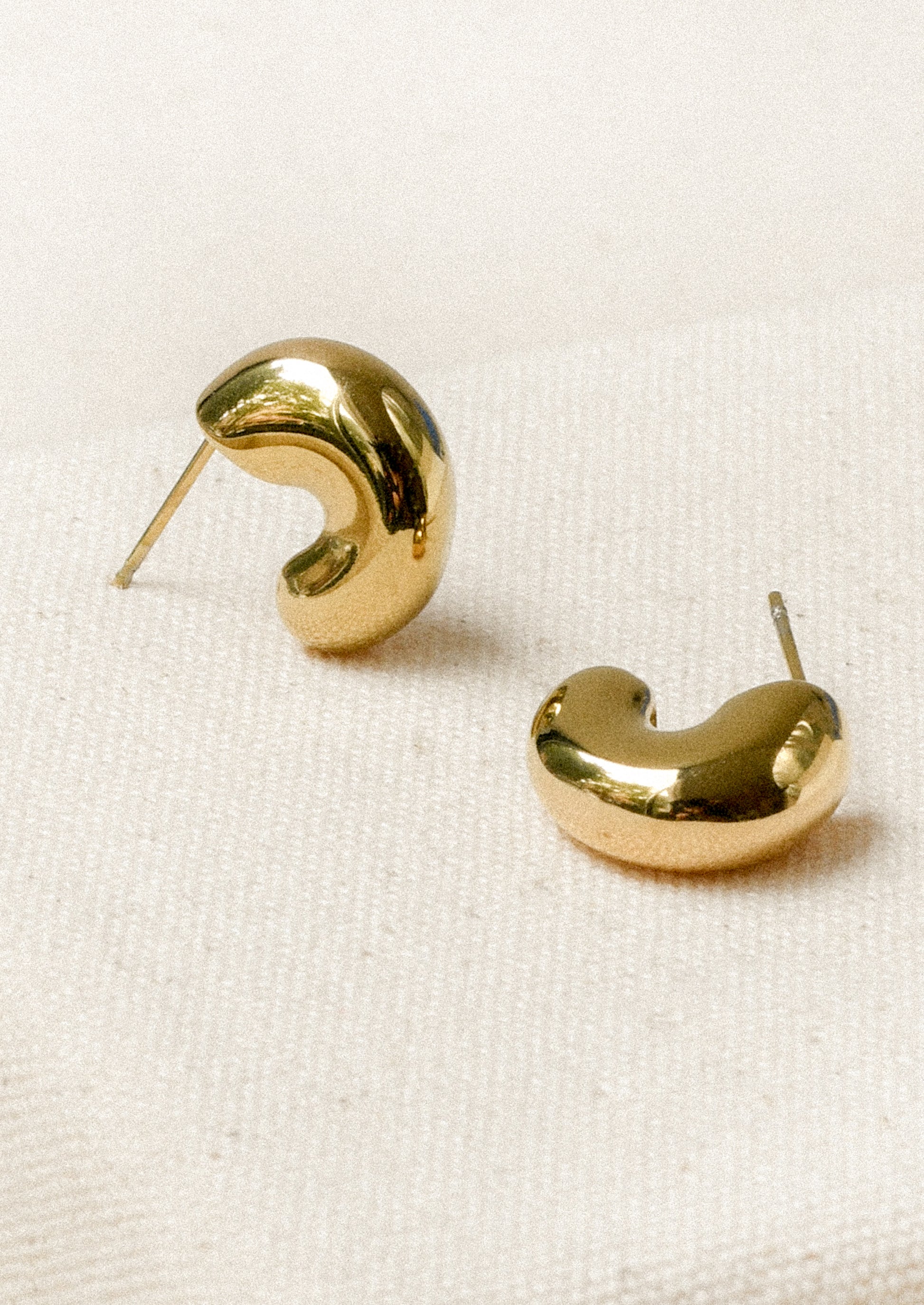 A pair of chunky gold half hoop earrings with post closures.