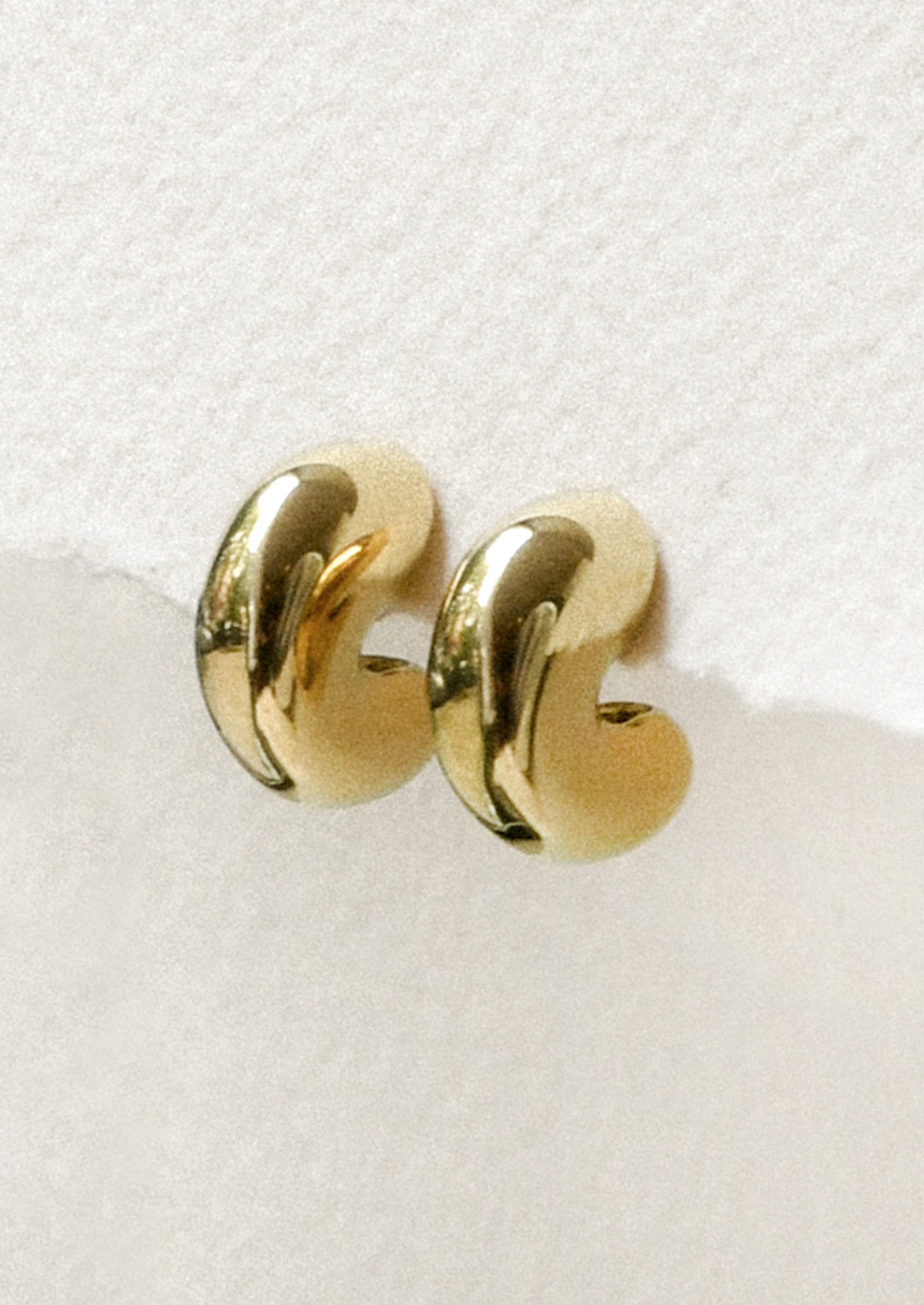 A pair of chunky gold half hoop earrings.