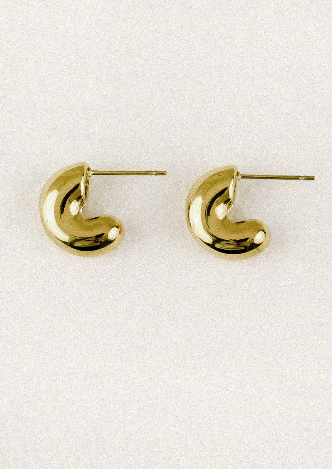 A pair of chunky gold half hoop earrings with post closures.