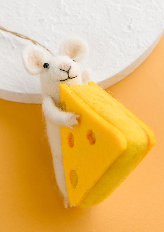 A felted wool ornament of white mouse and wedge of cheese. 