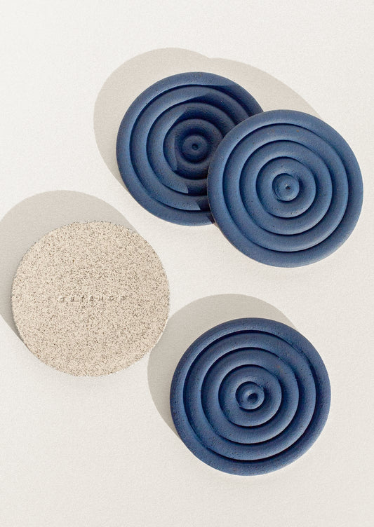 Handmade speckled ceramic coasters with a concentric design in cobalt blue.