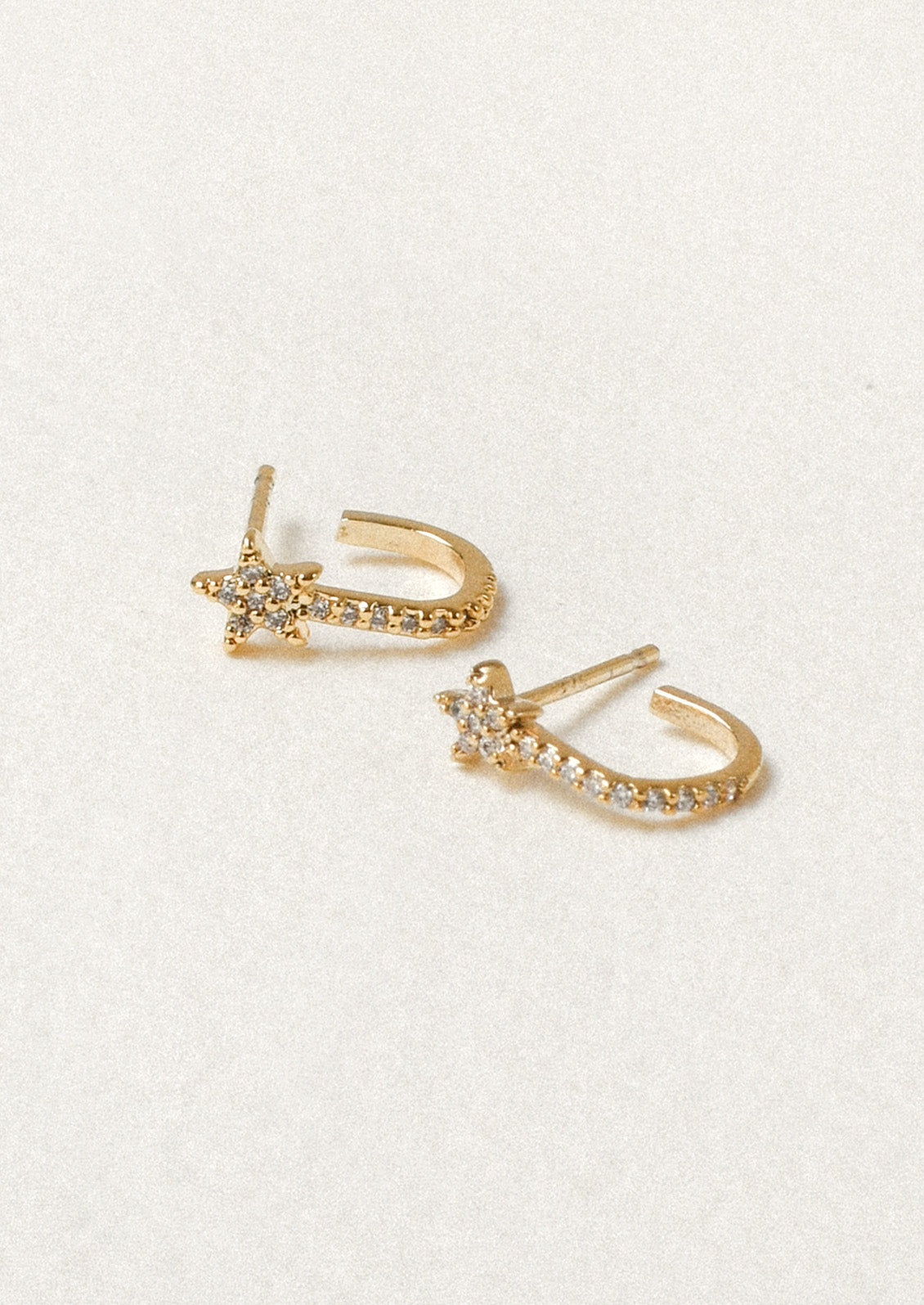 A pair of gold earrings with a comet star design and cubic zirconia gems throughout.