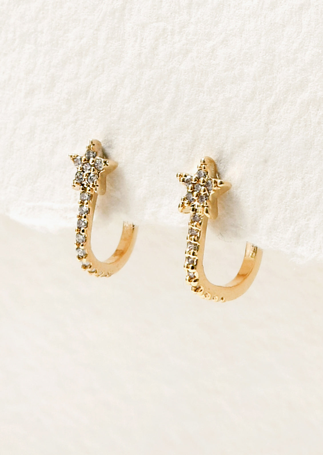A pair of gold earrings with a comet star design and cubic zirconia gems throughout.