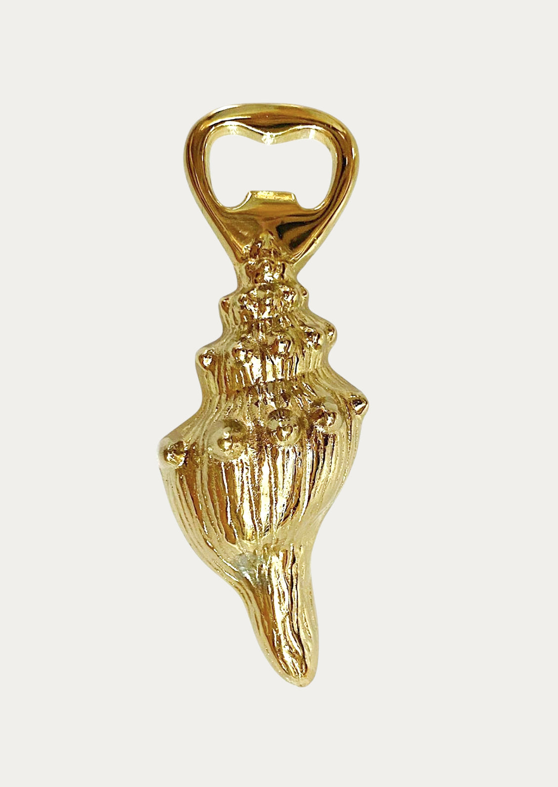 Gold bottle opener with conch design on a white background