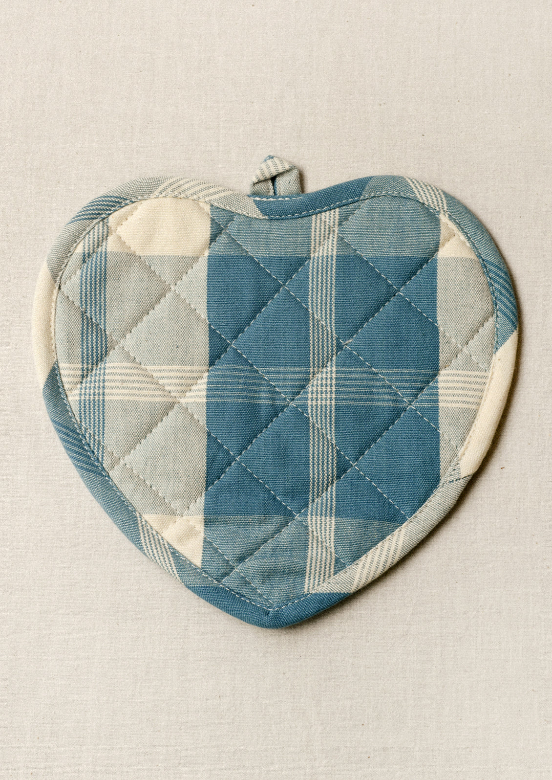 A heart shaped pot holder with a blue gingham pattern.