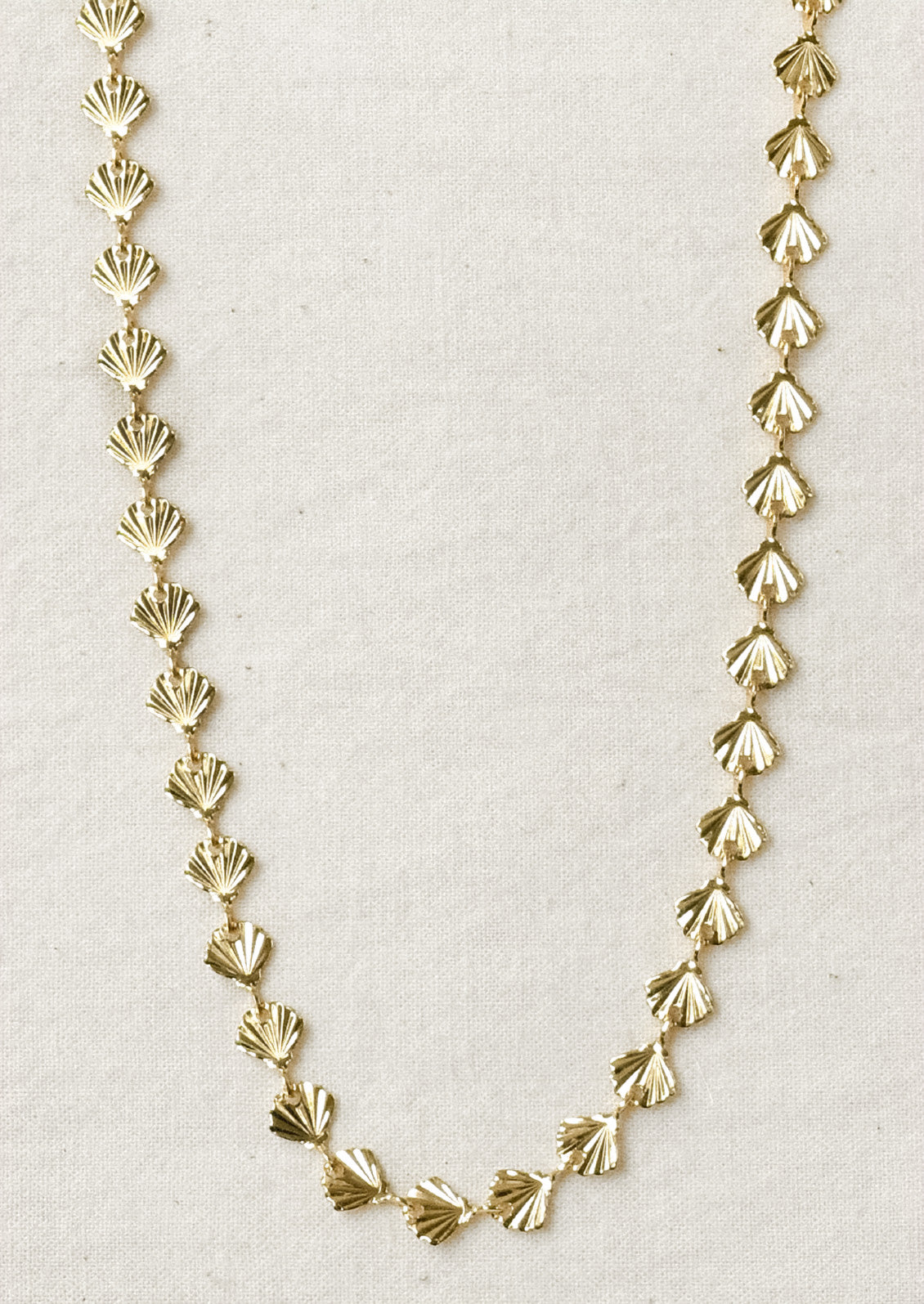 A gold necklace composed of tiny gold seashells.