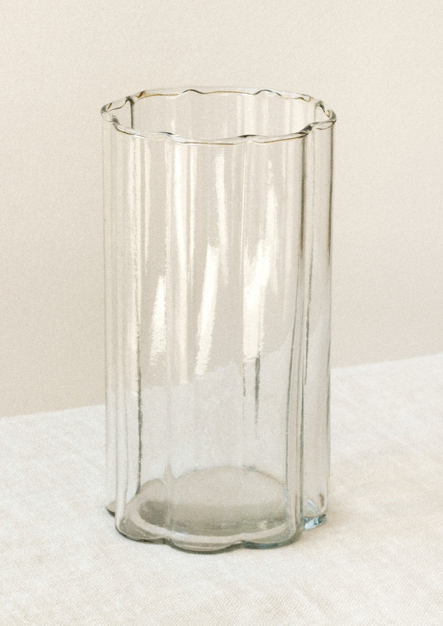 A clear glass cup with a scalloped rim.
