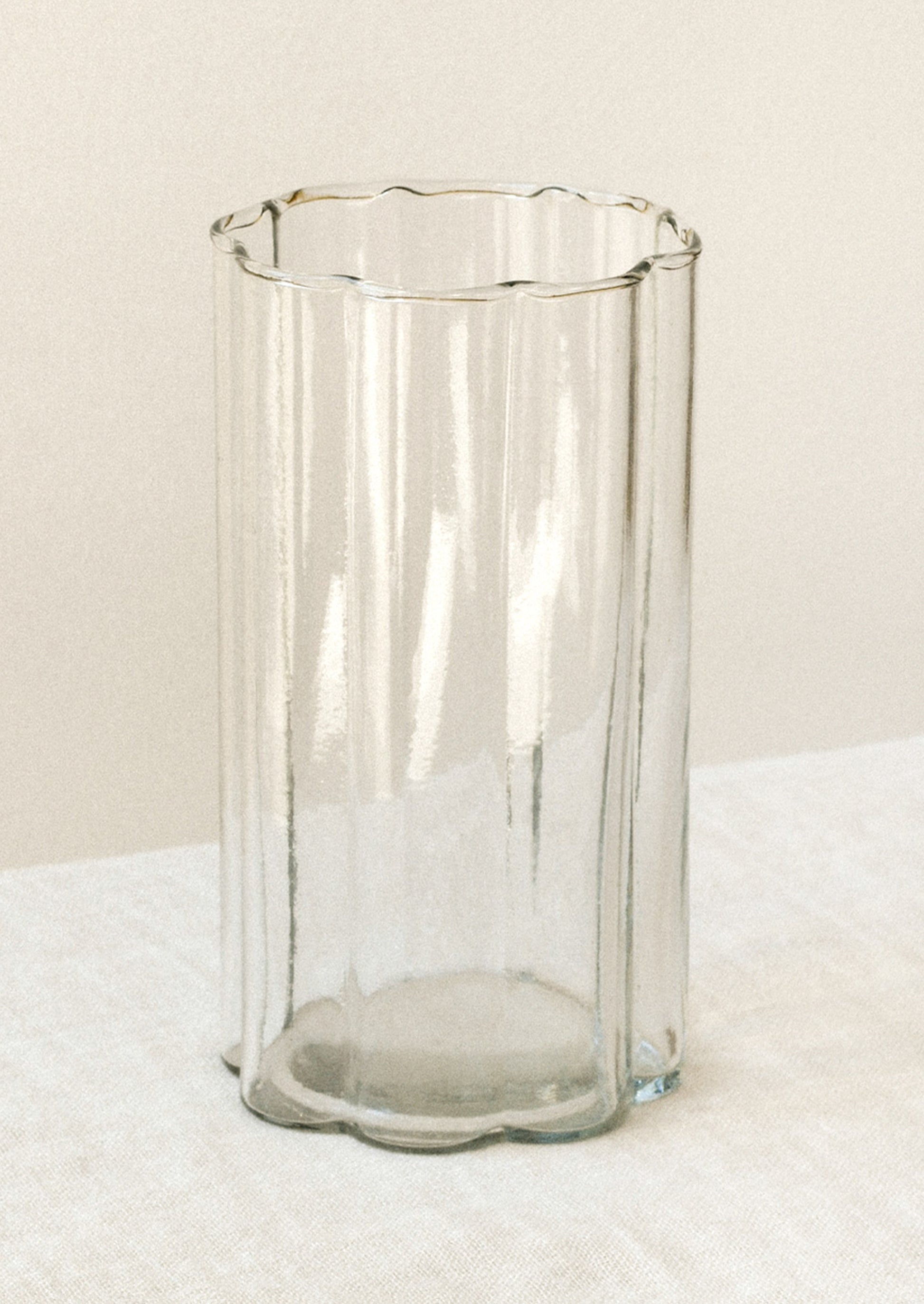 A clear glass cup with a scalloped rim.