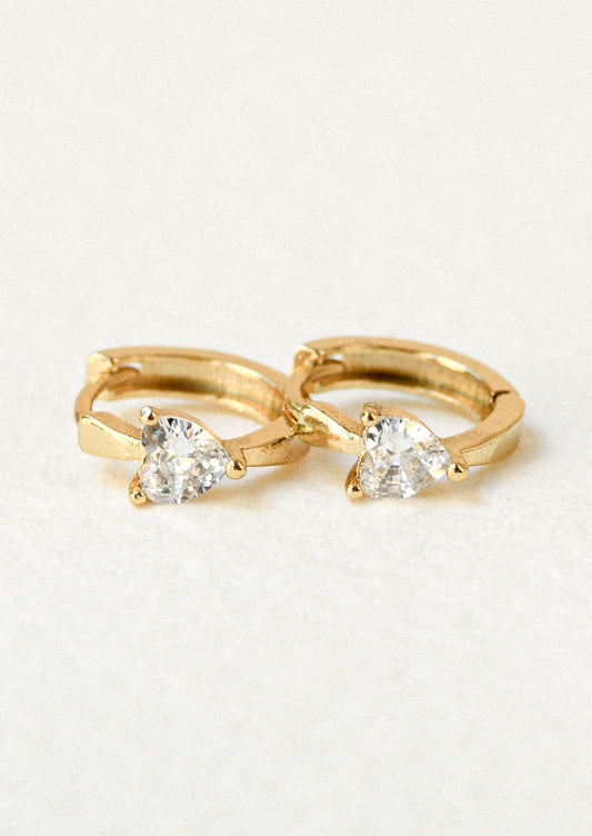 A pair of gold hoop earrings with heart shaped cubic zirconia gems.