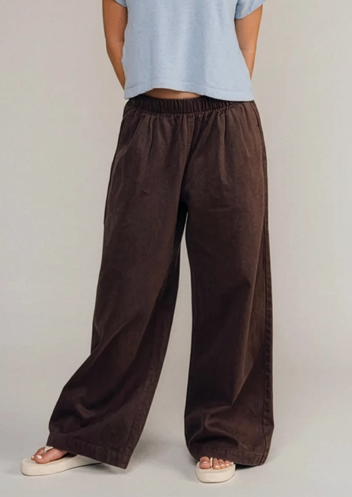 A person wearing a pair of loose brown pants.