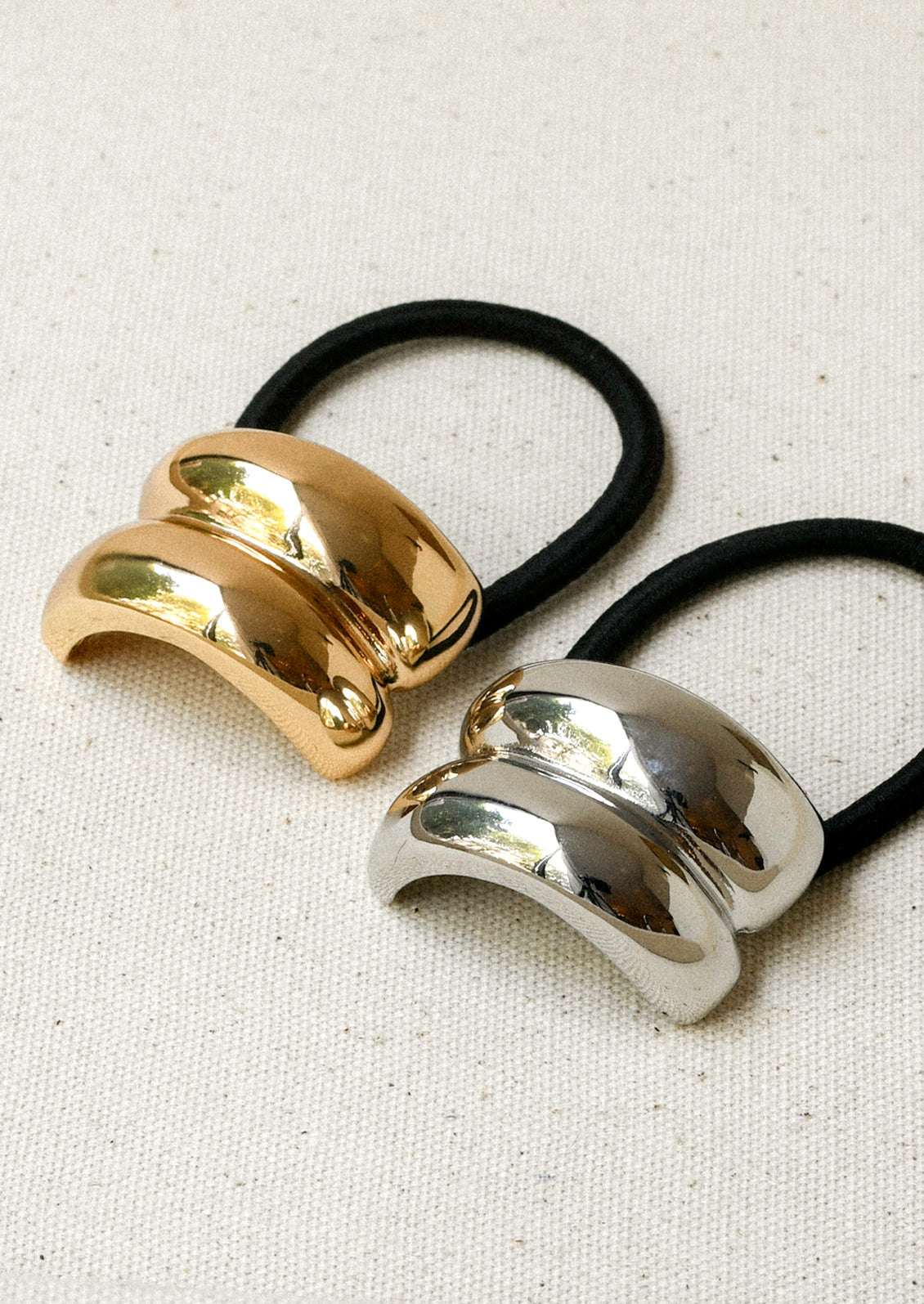 Black elastic hair ties with a gold and silver metal pendant with a double arch design.