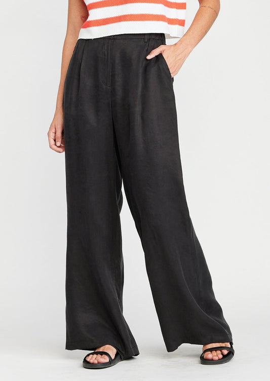 A woman wearing a pair of black wide leg pants in sateen cupro material.