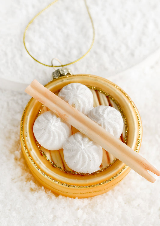 A glass ornament of tray of steamed buns with chopsticks.