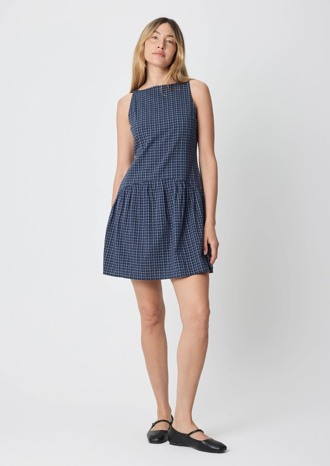 A person wearing a navy mini dress with white check pattern.