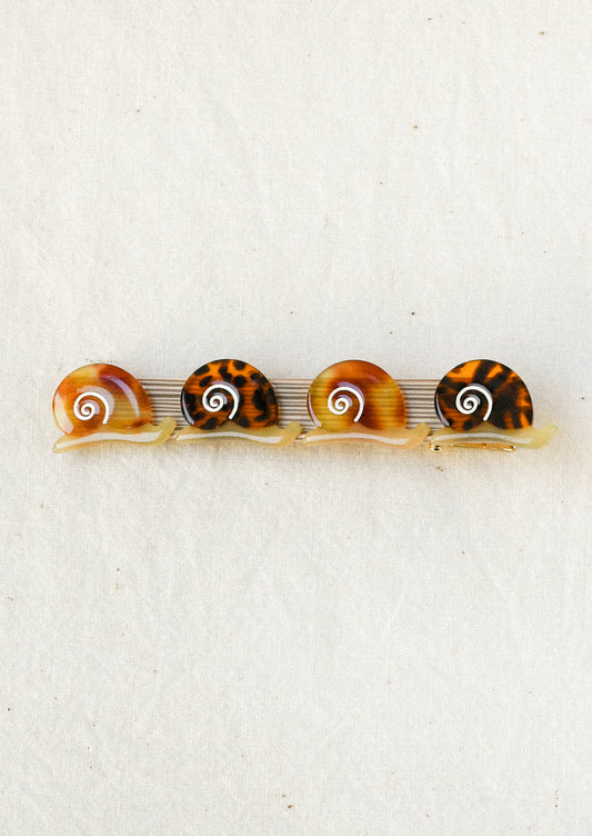 A gold hair barrette decorated with small brown snails with tortoise shell and gradient brown shell patterns.