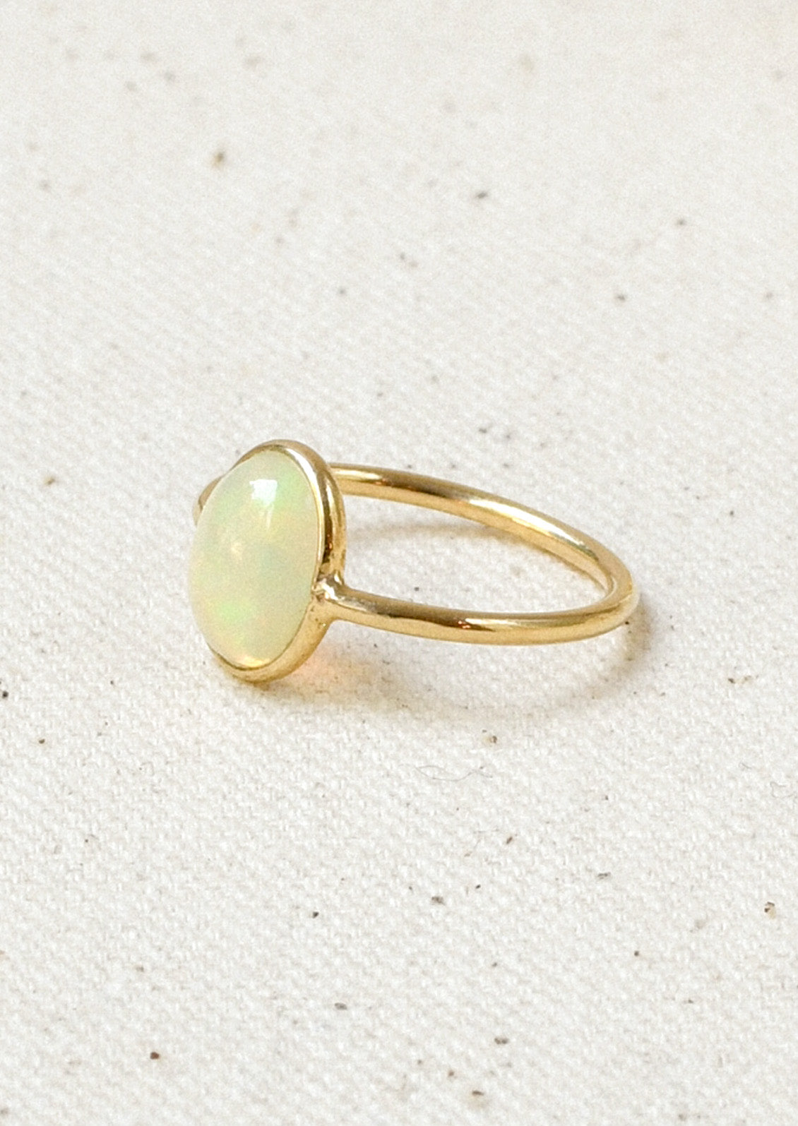 A gold ring with a natural Ethiopian opal bezeled in the center.