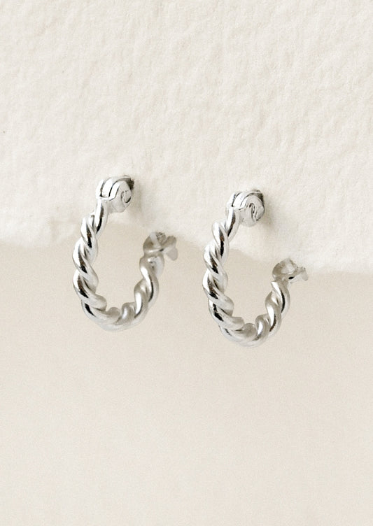 A pair of small silver hoop earrings with a twisted design.