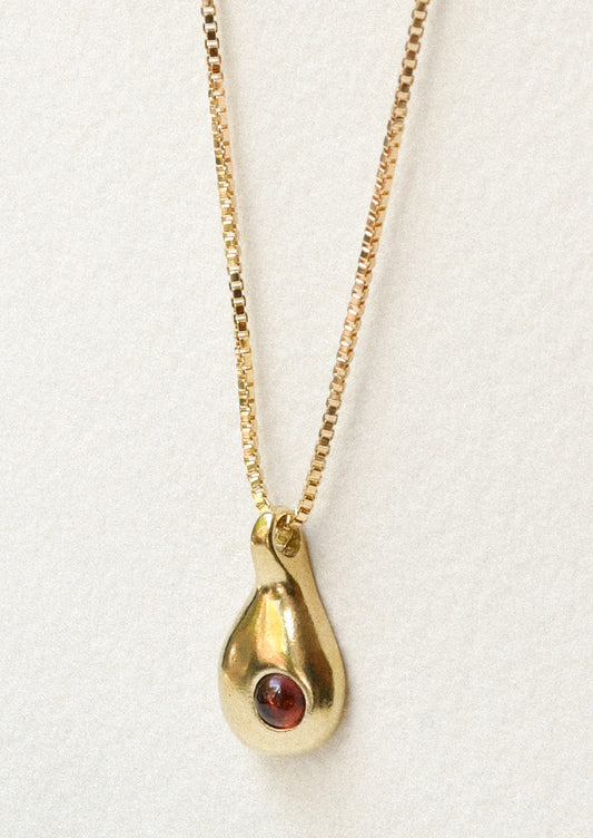 A bronze necklace with a droplet charm with a garnet on the front.